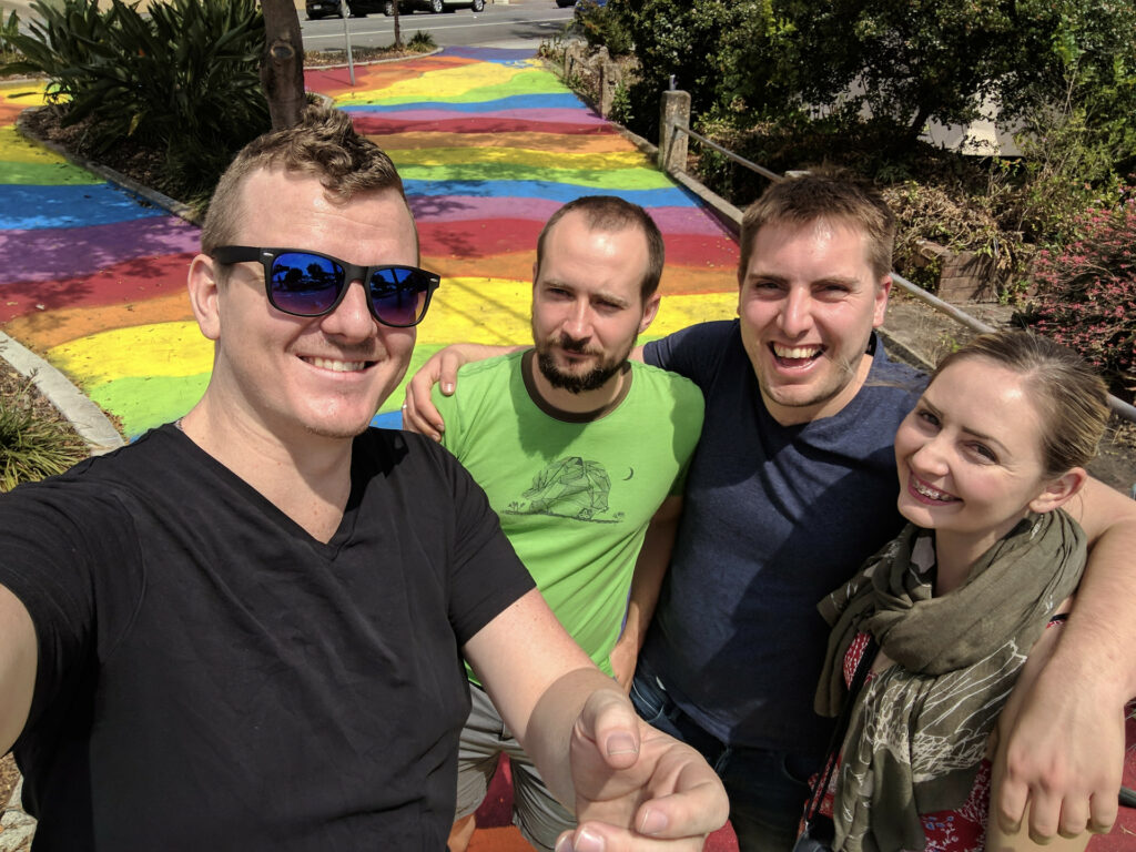 Myself, Joel, Tom & Shashi in front of a bright rainbow painted footpath. It's really something.