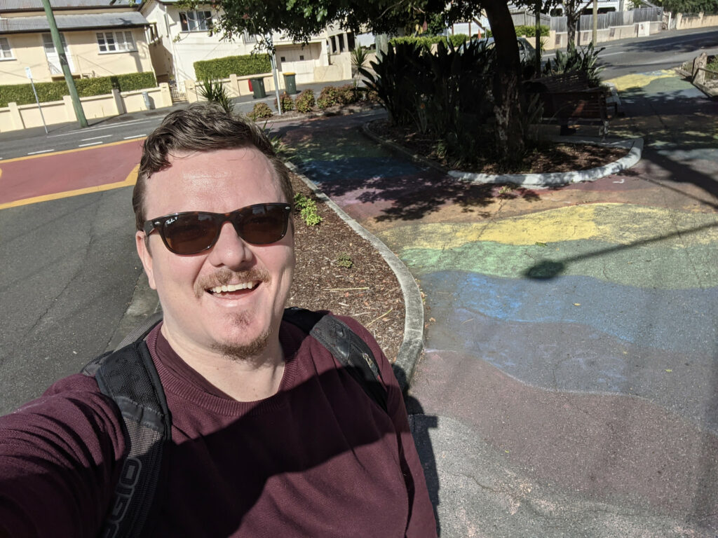 Me standing in front of the significantly faded rainbow sidewalk.