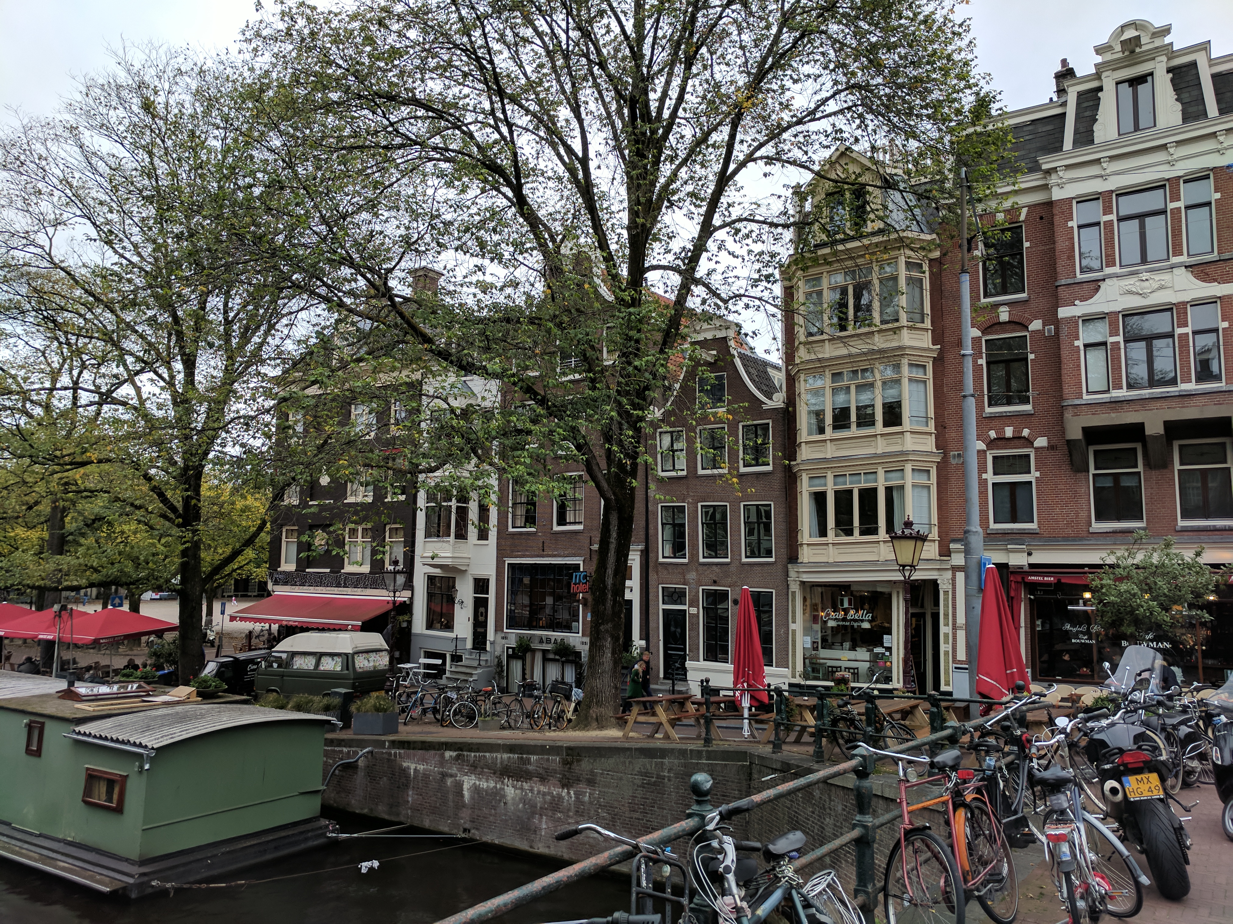 An Amsterdam street with tall narrow houses. A houseboat in the foreground.