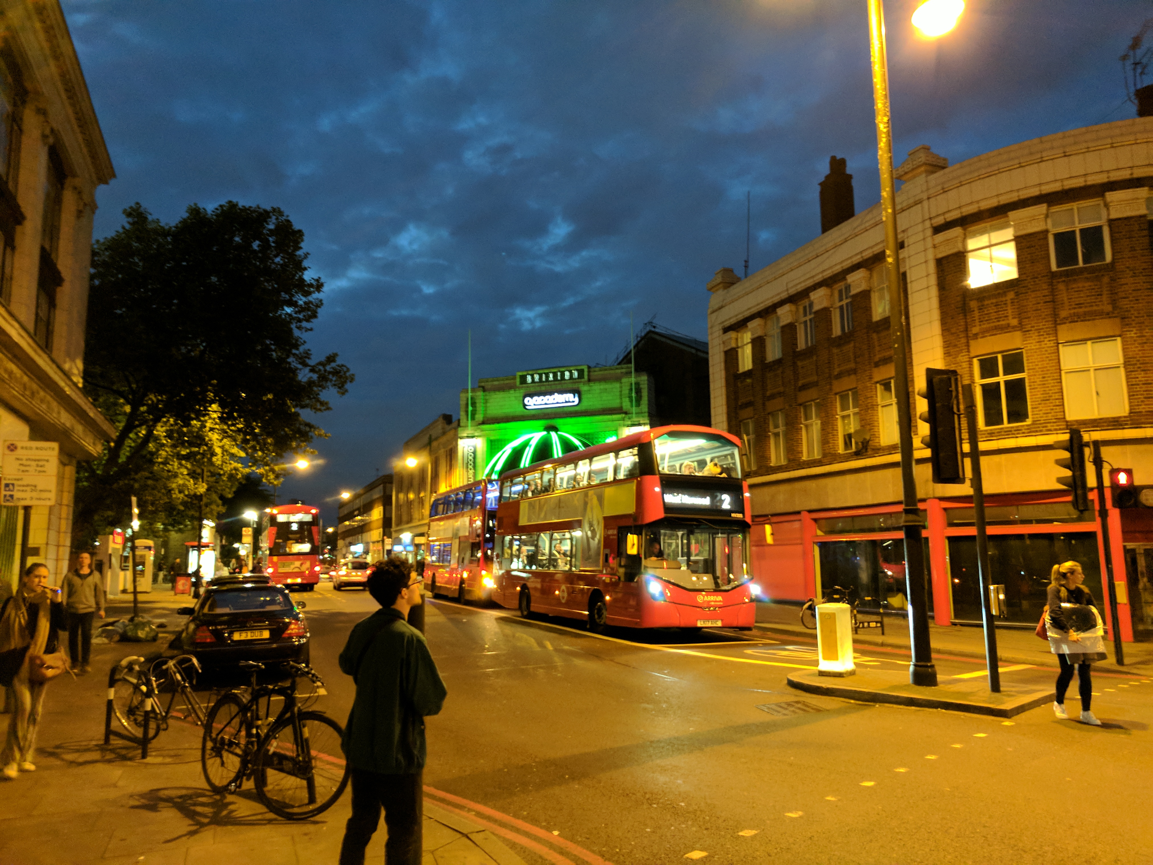 Brixton Academy illuminated in neon green, a double decker london bus in the foreground.