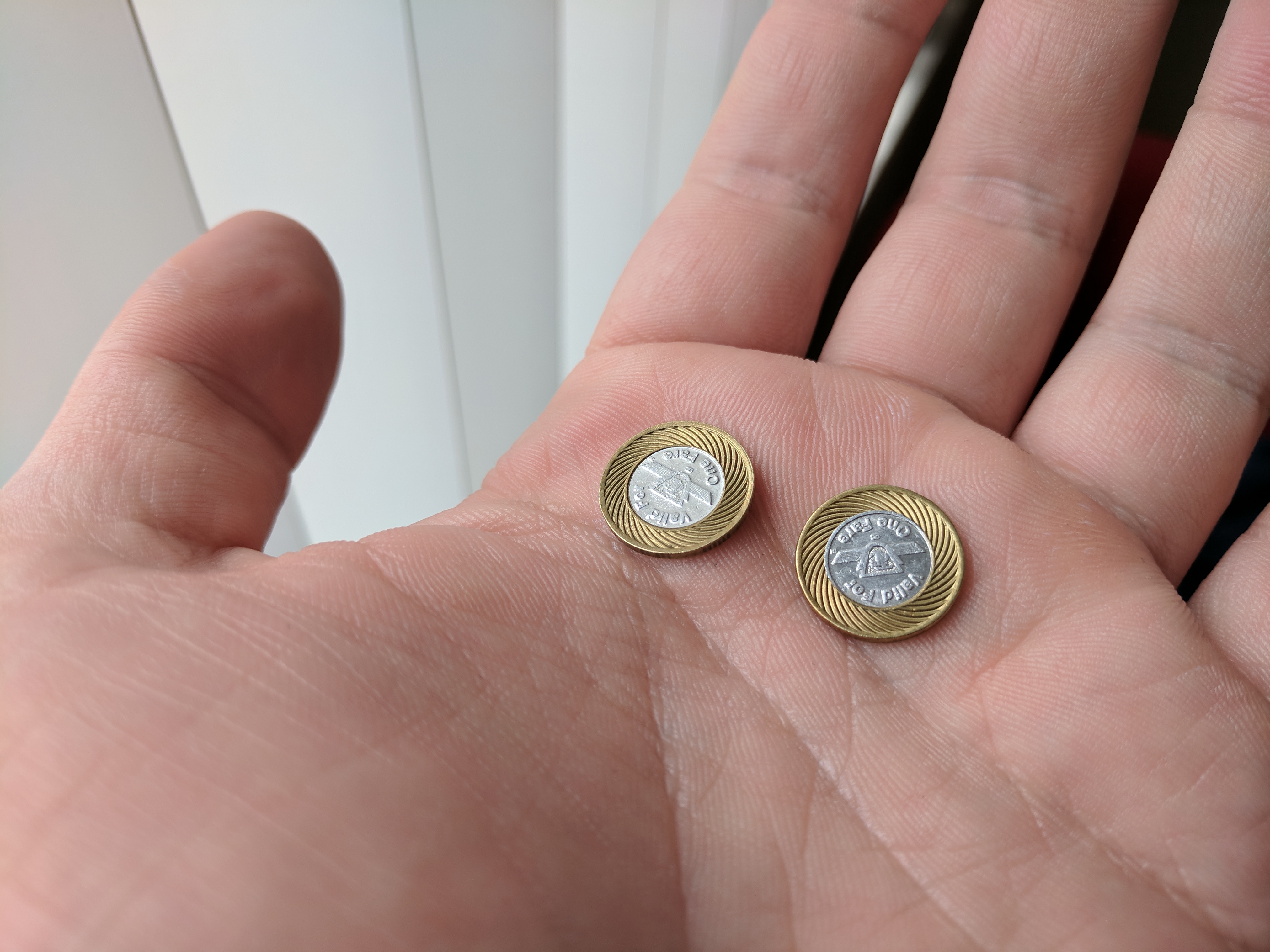 Two subway tokens close up in my hand