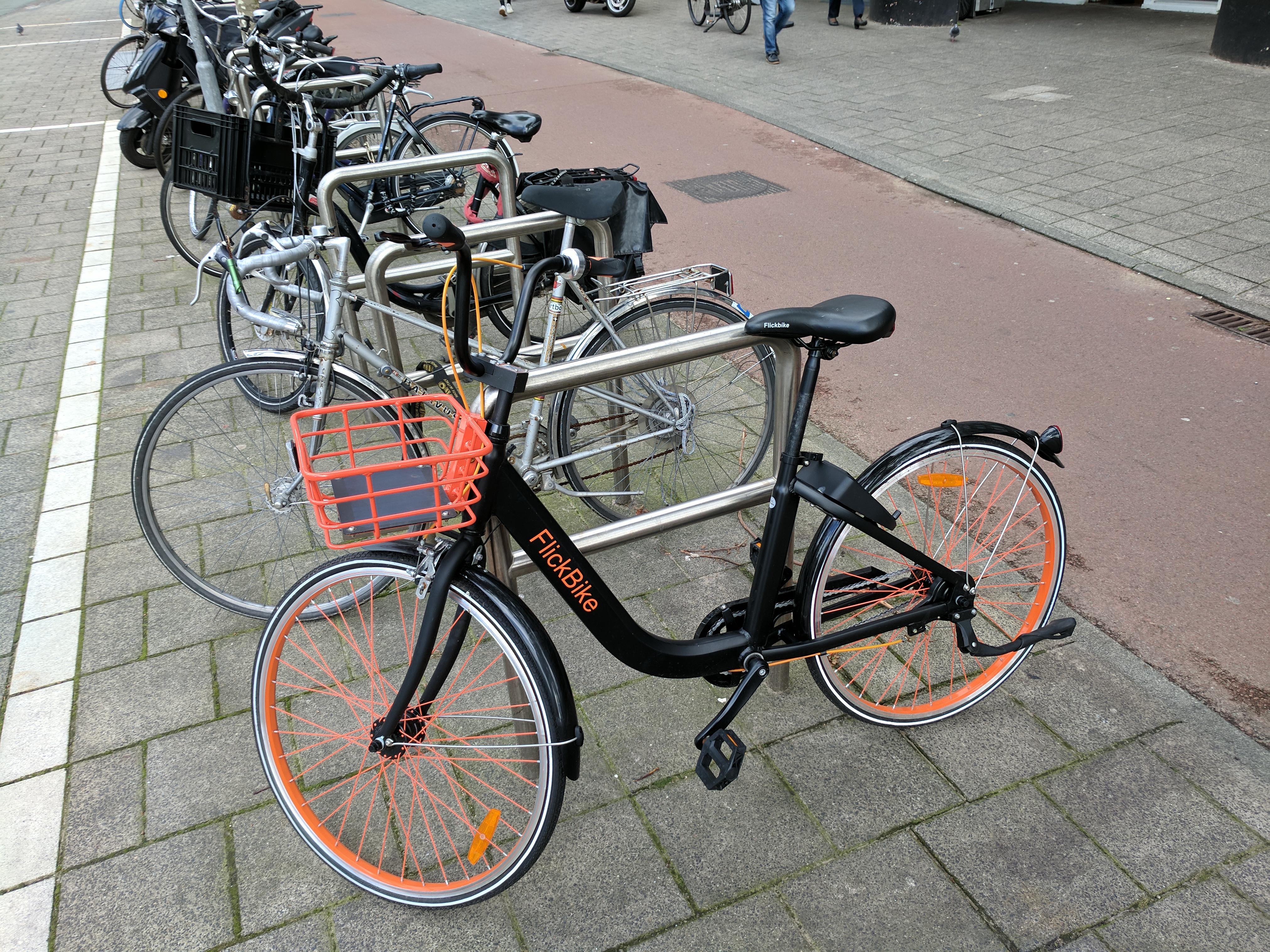 A FlickBike rental bike tied to a bike loop next to the bikeway.