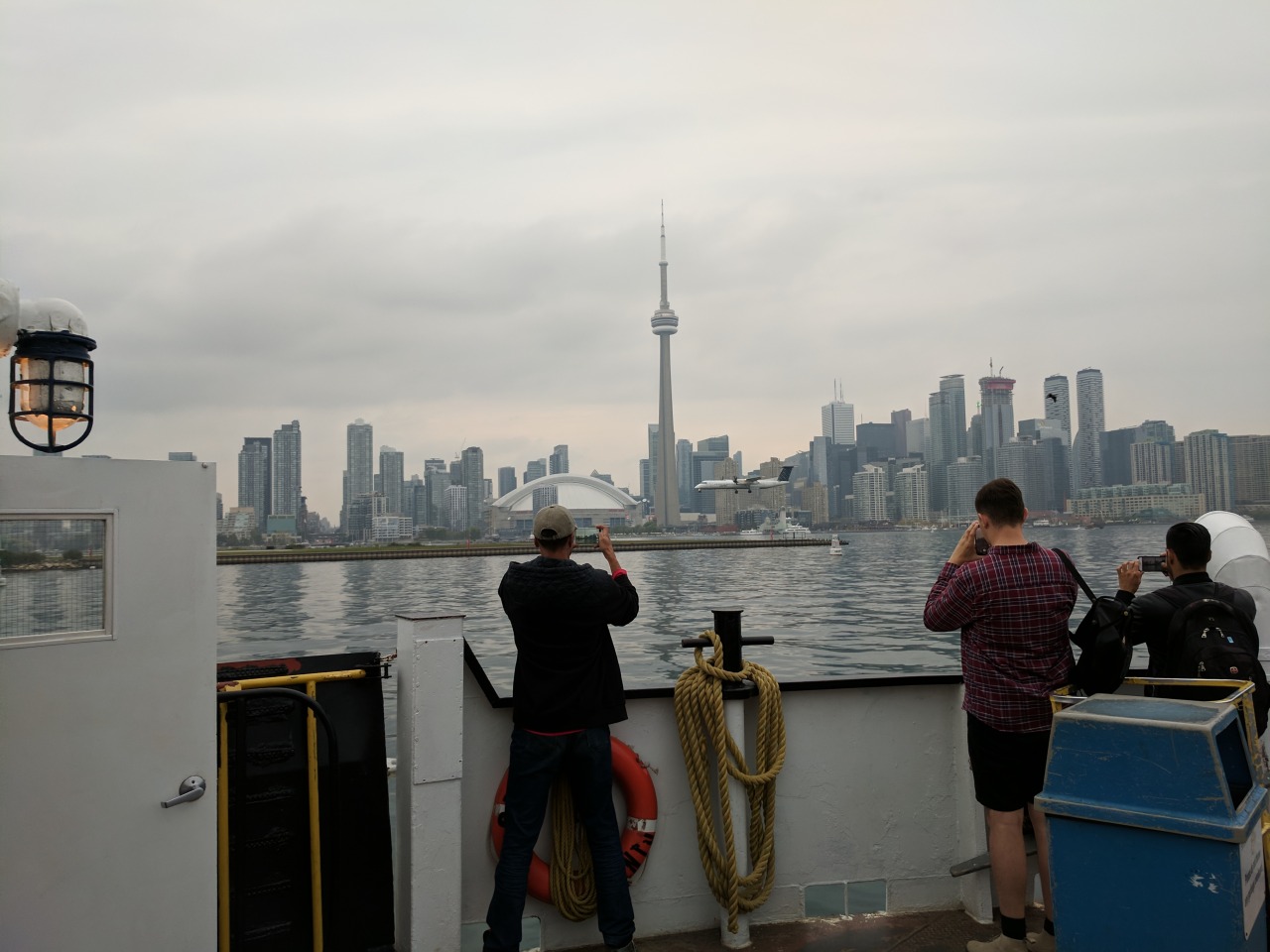People on a boat taking photos of a plane landing at Toronto Airport