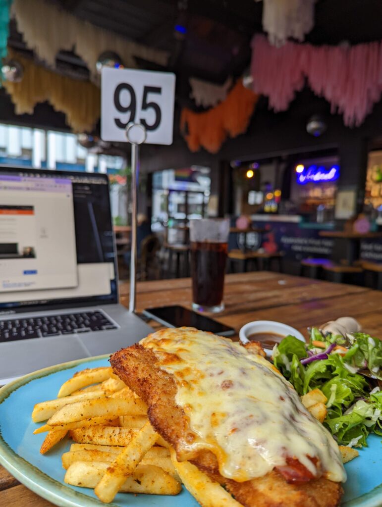 Chicken parmy with chippies and salad. So good. Laptop set up in the background, and the bar out of focus on the distance
