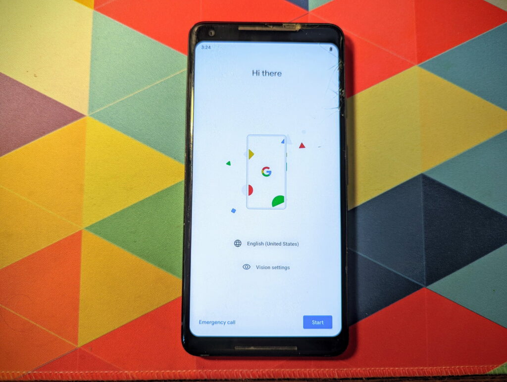 A Pixel 2 XL on a bright background. It's showing the welcome screen after being factory reset. There are cracks all over the screen.