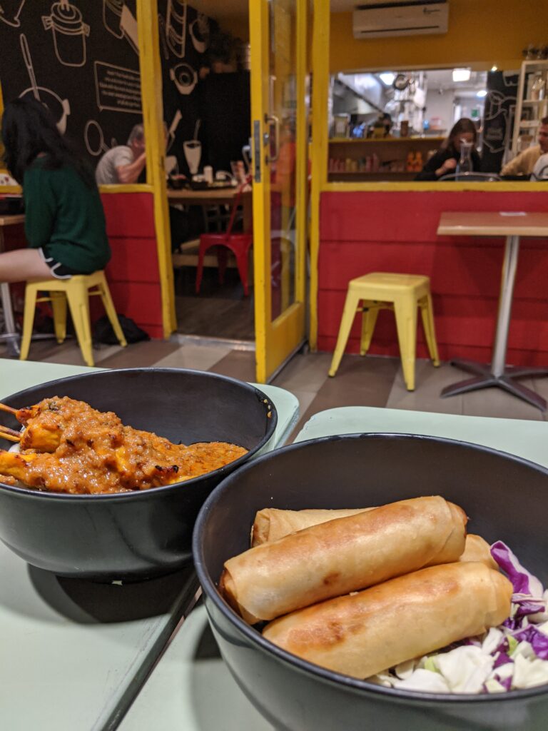 Skewers and spring rolls at a restaurant decorated in bright red and yellow.