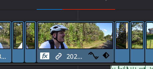 A DaVinci Resolve timeline showing a half-completed render cache over a clip of me riding a bike.